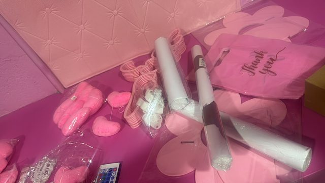 Las cajas rosadas de la decoración recién desempacadas en el piso, con una tarjeta de agradecimiento encima