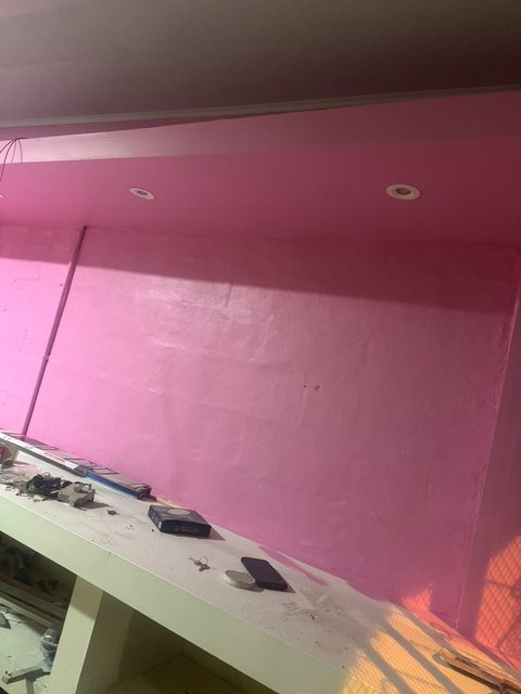 La pared principal ya pintada de rosa, con los rieles del cielo raso a la vista