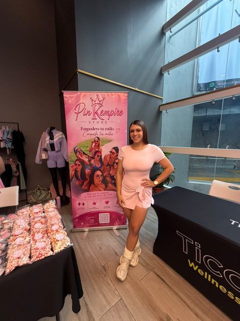 Kendolly junto al banner de PinKempire en su stand de la feria, con la mesa de productos armada