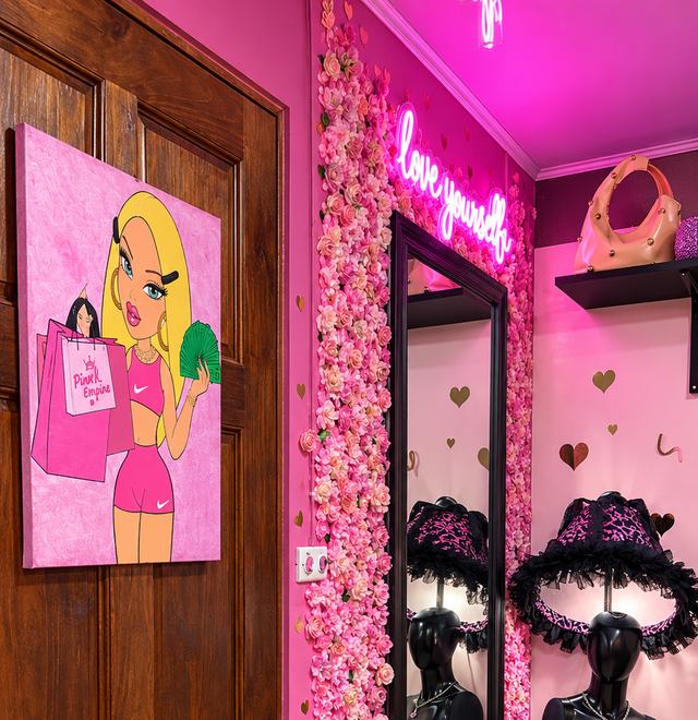 Letrero de neón que dice love yourself, junto al espejo y la pared de flores rosadas